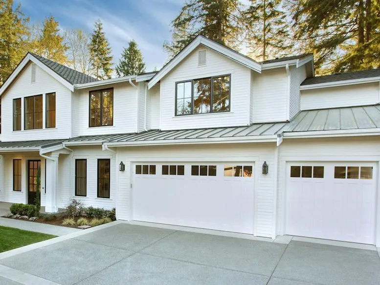 White farmhouse with Hörmann carriage house garage doors